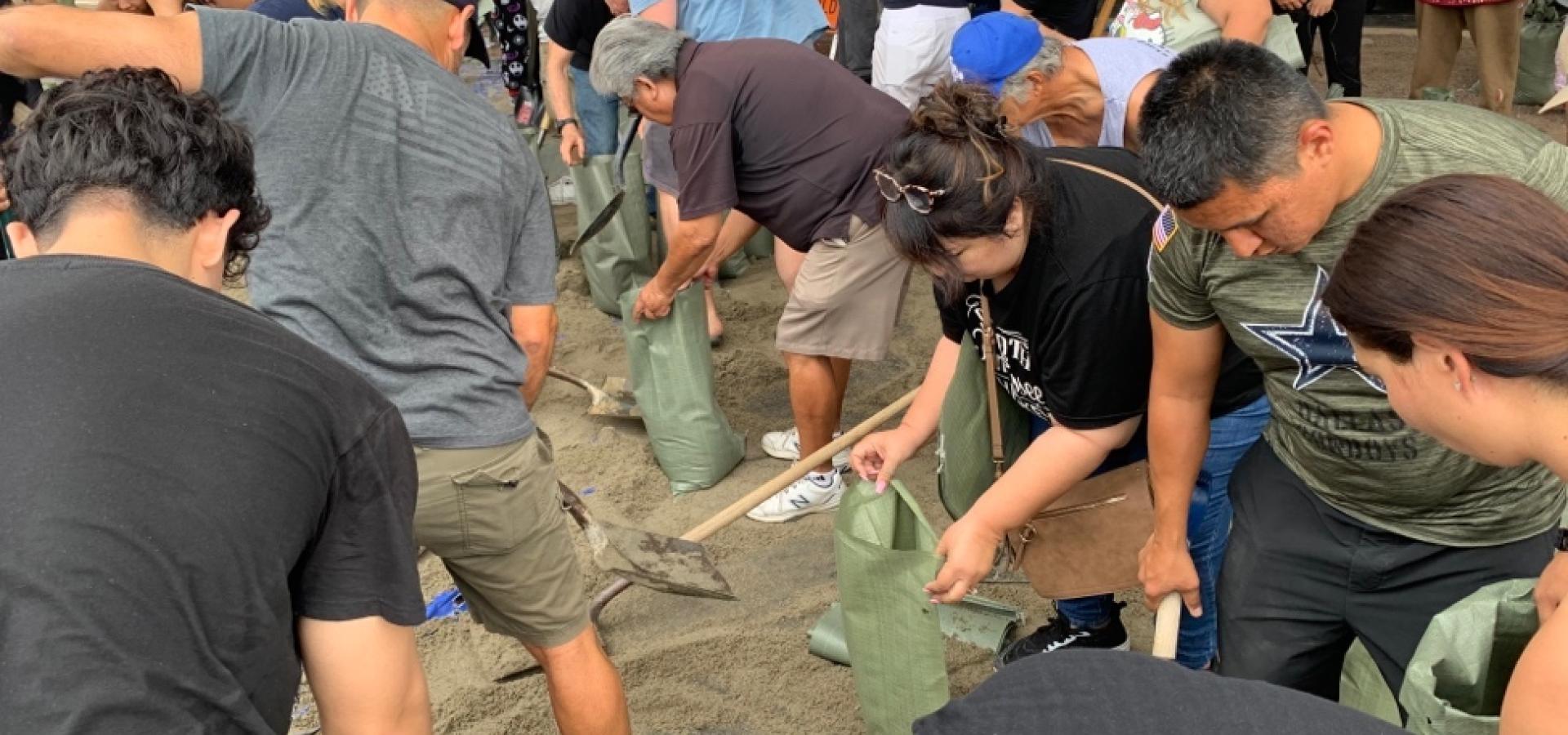 Congressman Ruiz shoveling sand with community member to fill sandbags 